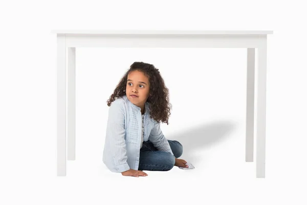 Menina americana africana sentada debaixo da mesa — Fotografia de Stock