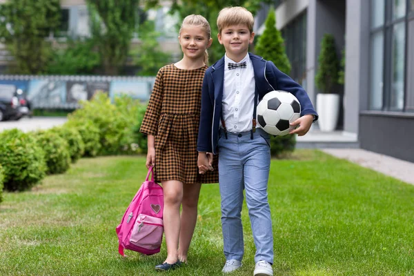 Écoliers avec sac à dos et ballon de football — Photo de stock