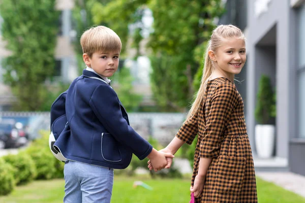 Cute schoolchildren holding hands — Stock Photo