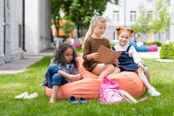 Multiethnic schoolgirls reading book — Stock Photo