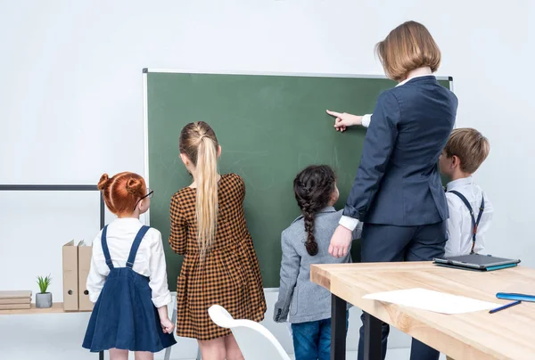 Teacher with students at blackboard — Stock Photo