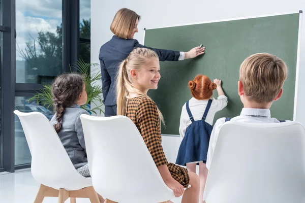 Enseignant avec étudiant au tableau noir — Photo de stock