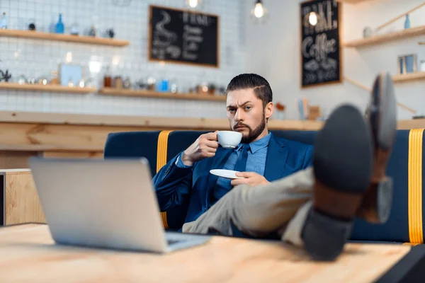Empresario usando laptop en cafetería — Stock Photo