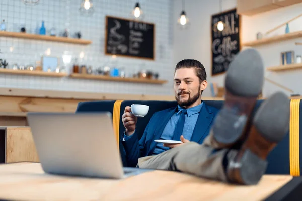 Empresario usando laptop en cafetería - foto de stock