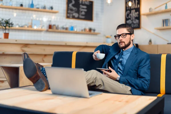 Empresario usando laptop en cafetería - foto de stock