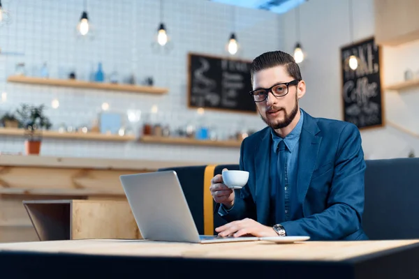 Empresario usando laptop en cafetería - foto de stock