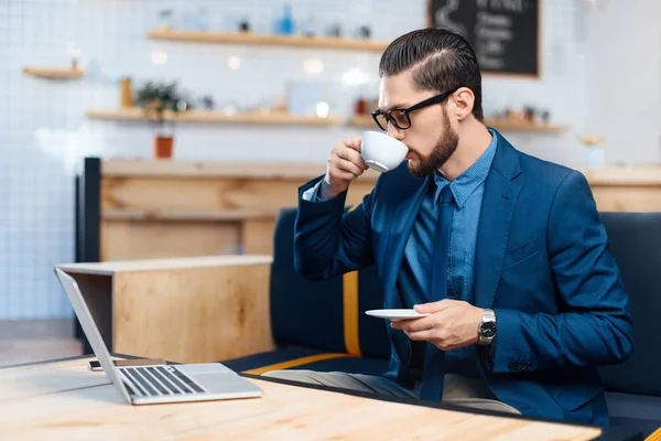 Empresario usando laptop en cafetería — Stock Photo