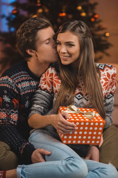 Man kissing girlfriend with christmas present — Stock Photo