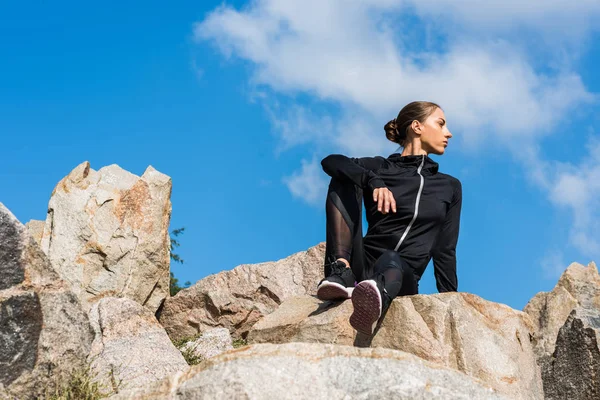 Mujer sentada sobre rocas - foto de stock