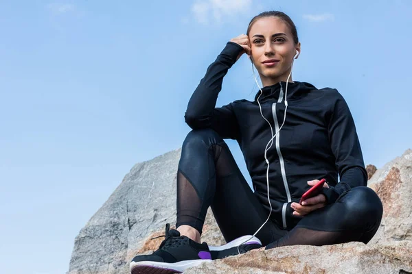 Mujer escuchando música en rocas - foto de stock