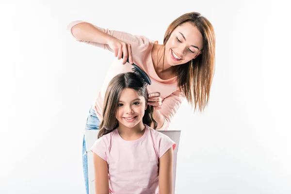 Madre peinando hijas cabello - foto de stock