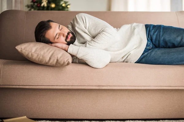 Bel homme en pull dormant sur le canapé — Photo de stock