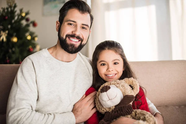 Vater umarmt Tochter mit Teddybär und blickt in Kamera — Stockfoto