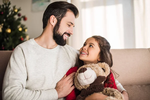 Padre abrazando hija con osito de peluche - foto de stock