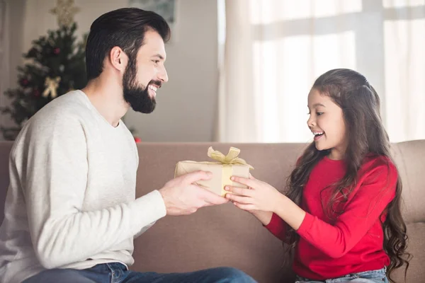 Smiling father presenting gift box to daughter — Stock Photo