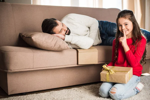 Hija sentada con presente y mostrando señal de silencio - foto de stock