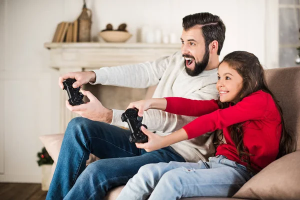 Feliz padre e hija jugando videojuegos en casa - foto de stock