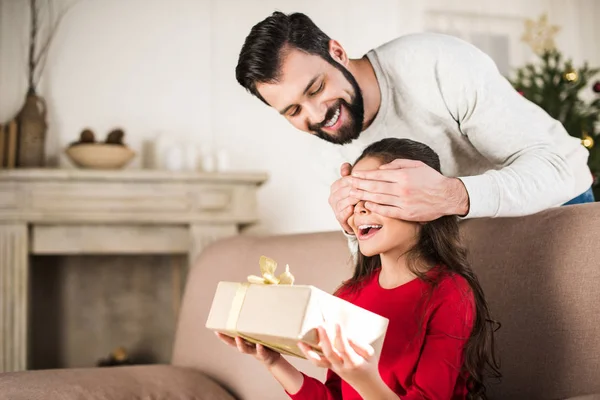 Vater deckt Tochter die Augen von hinten zu und überreicht Geschenk — Stockfoto