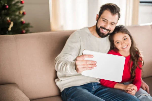Father and daughter taking selfie sitting on sofa at home — Stock Photo