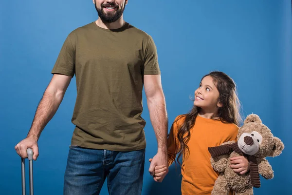 Imagen recortada de la hija y el padre tomados de la mano en azul - foto de stock