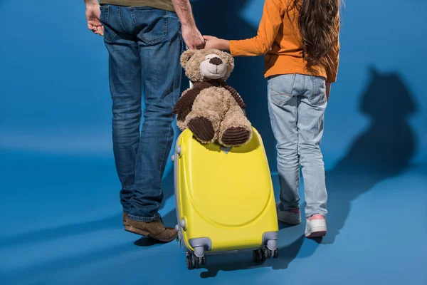Cropped image of father and daughter going with travel bag on blue — Stock Photo