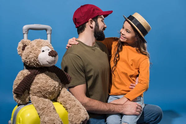 Daughter sitting on father knee and looking at each other on blue — Stock Photo