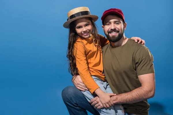 Daughter sitting on father knee on blue — Stock Photo