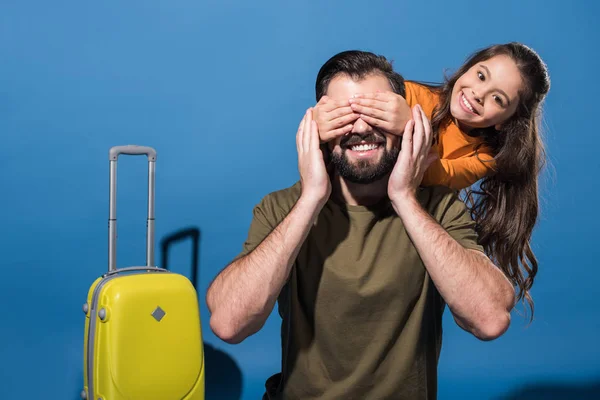 Hija cubriendo padre ojos de vuelta en azul - foto de stock