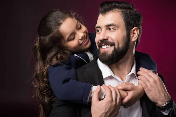 Figlia abbracciando il padre dalla schiena e si guardano a vicenda sul bordeaux — Foto stock