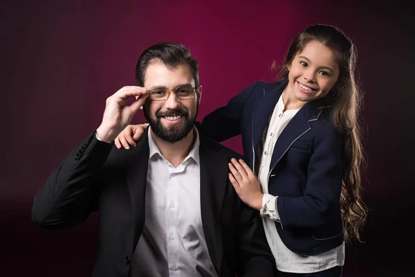 Vater berührt Brille und blickt in Kamera auf weinrotem Grund — Stockfoto