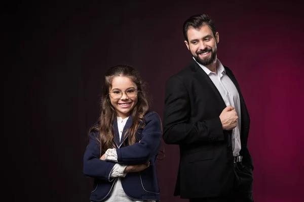 Hija sonriente con las manos cruzadas mirando a la cámara en color burdeos - foto de stock