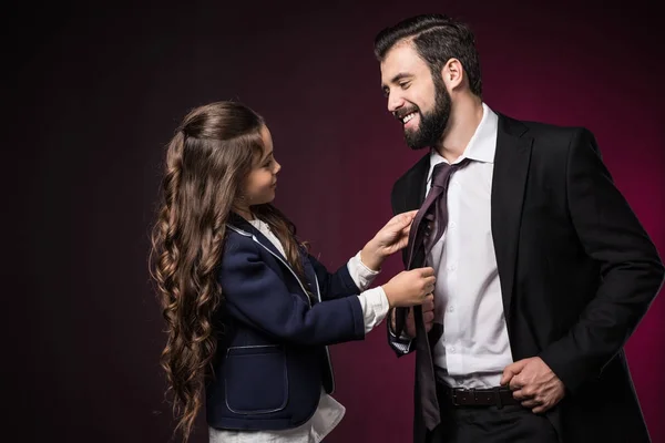 Daughter fixing smiling father tie on burgundy — Stock Photo