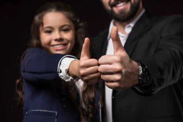 Cropped image of father and daughter showing thumbs up on burgundy — Stock Photo