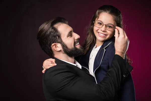 Father fixing daughter glasses on burgundy — Stock Photo