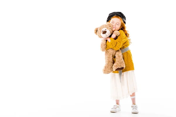 Enfant roux souriant étreignant ours en peluche avec les yeux fermés isolé sur blanc — Photo de stock