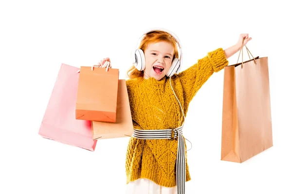 Rotschopfiges Kind singt und hält Einkaufstüten isoliert auf weißem Grund — Stockfoto