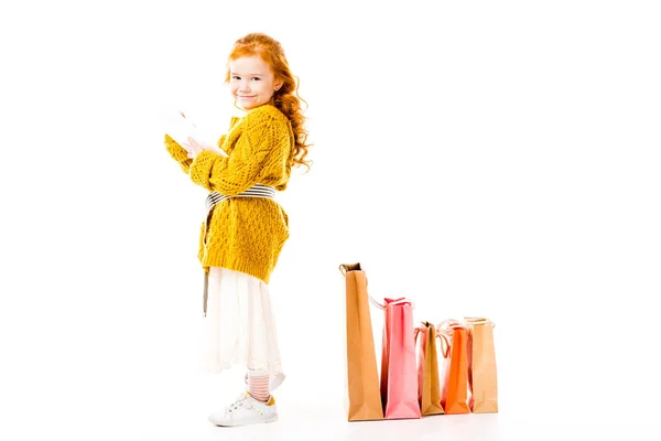 Side view of redhead kid holding tablet and looking at camera isolated on white — Stock Photo