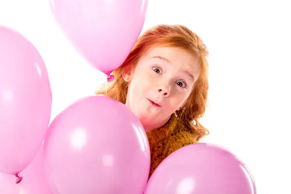 Smorzare i capelli rossi bambino in piedi con fascio di palloncini rosa isolati su bianco — Foto stock