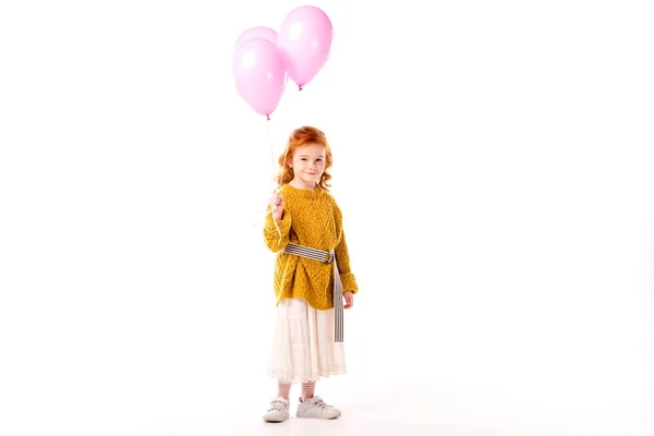 Niño de pelo rojo feliz sosteniendo globos rosados aislados en blanco - foto de stock