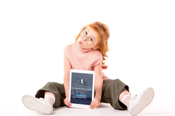 Rotes Haar Kind sitzt und hält Tablet mit geladener Tumblr-Seite auf weiß — Stockfoto