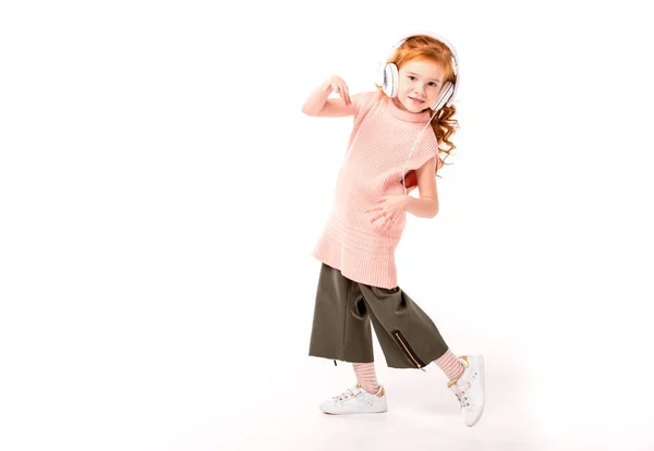 Pelo rojo niño en auriculares bailando y mirando a la cámara en blanco - foto de stock