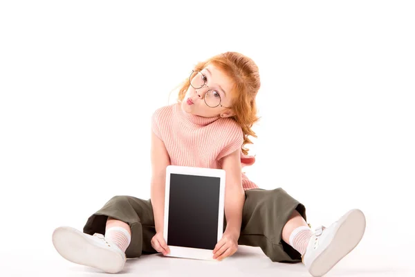 Bambino con i capelli rossicci seduto e mostrando tablet su bianco — Foto stock