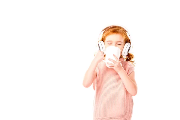 Pelirroja bebiendo té y escuchando música en auriculares aislados en blanco - foto de stock