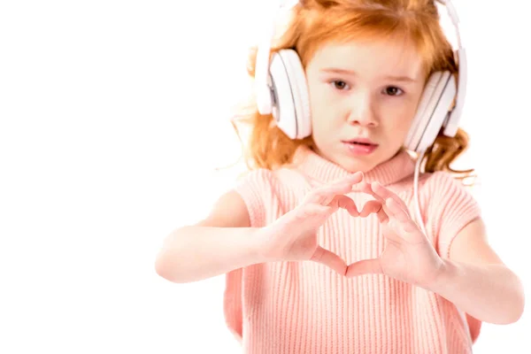 Cheveu roux enfant dans les écouteurs montrant coeur avec les doigts isolés sur blanc — Photo de stock