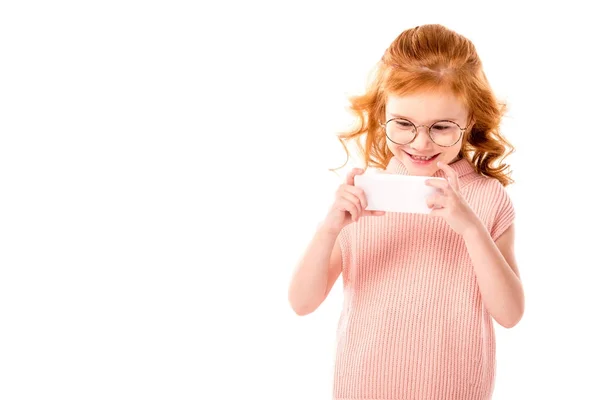 Дитина з імбирним волоссям робить фотографію зі смартфоном ізольовано на білому — стокове фото