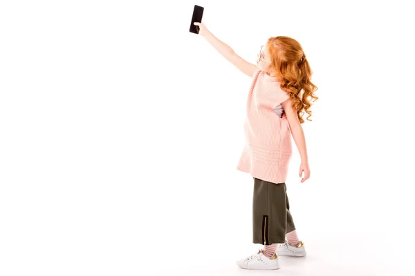 Redhead kid taking selfie with smartphone on white — Stock Photo