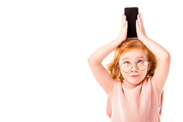 Funny red hair kid holding smartphone on head isolated on white — Stock Photo