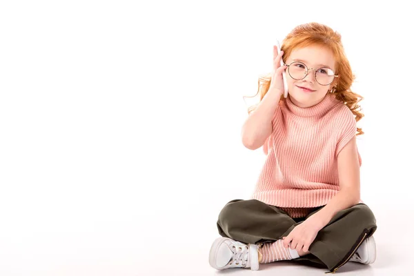 Ребенок с рыжими волосами разговаривает по смартфону на белом — стоковое фото