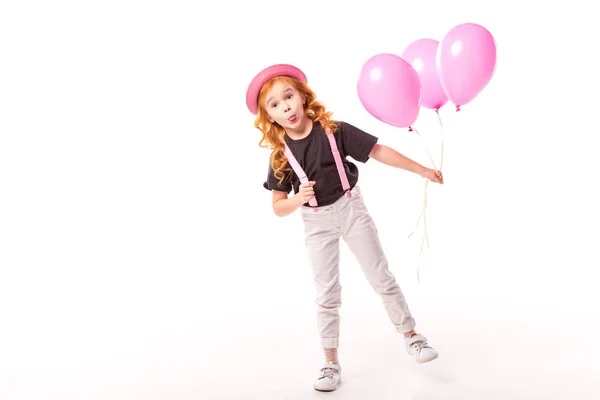 Grimacing red hair kid standing with pink balloons on white — Stock Photo