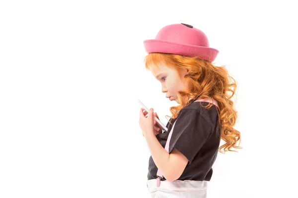 Vista laterale di riflessivo bambino capelli rossi guardando smartphone isolato su bianco — Foto stock